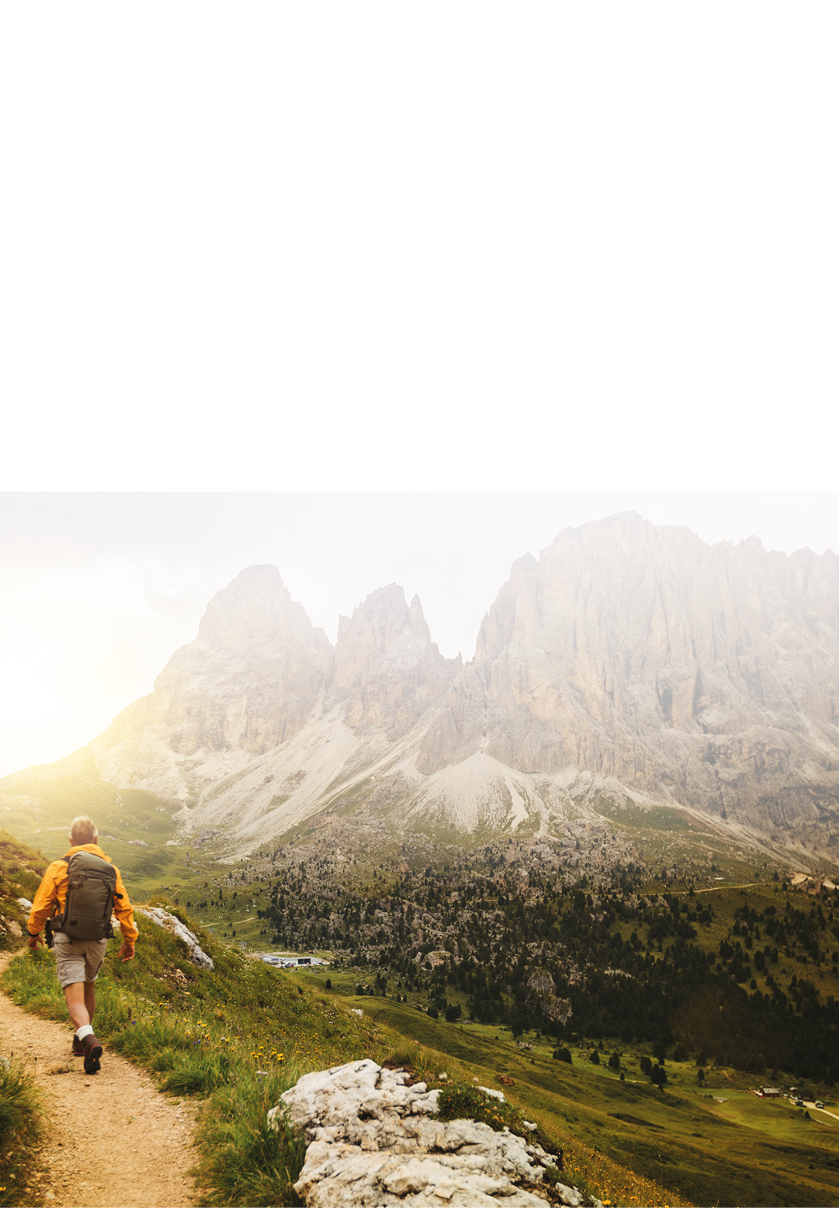 Senior man trail hiking on high mountain: by the Sella pass, with Saslong on background