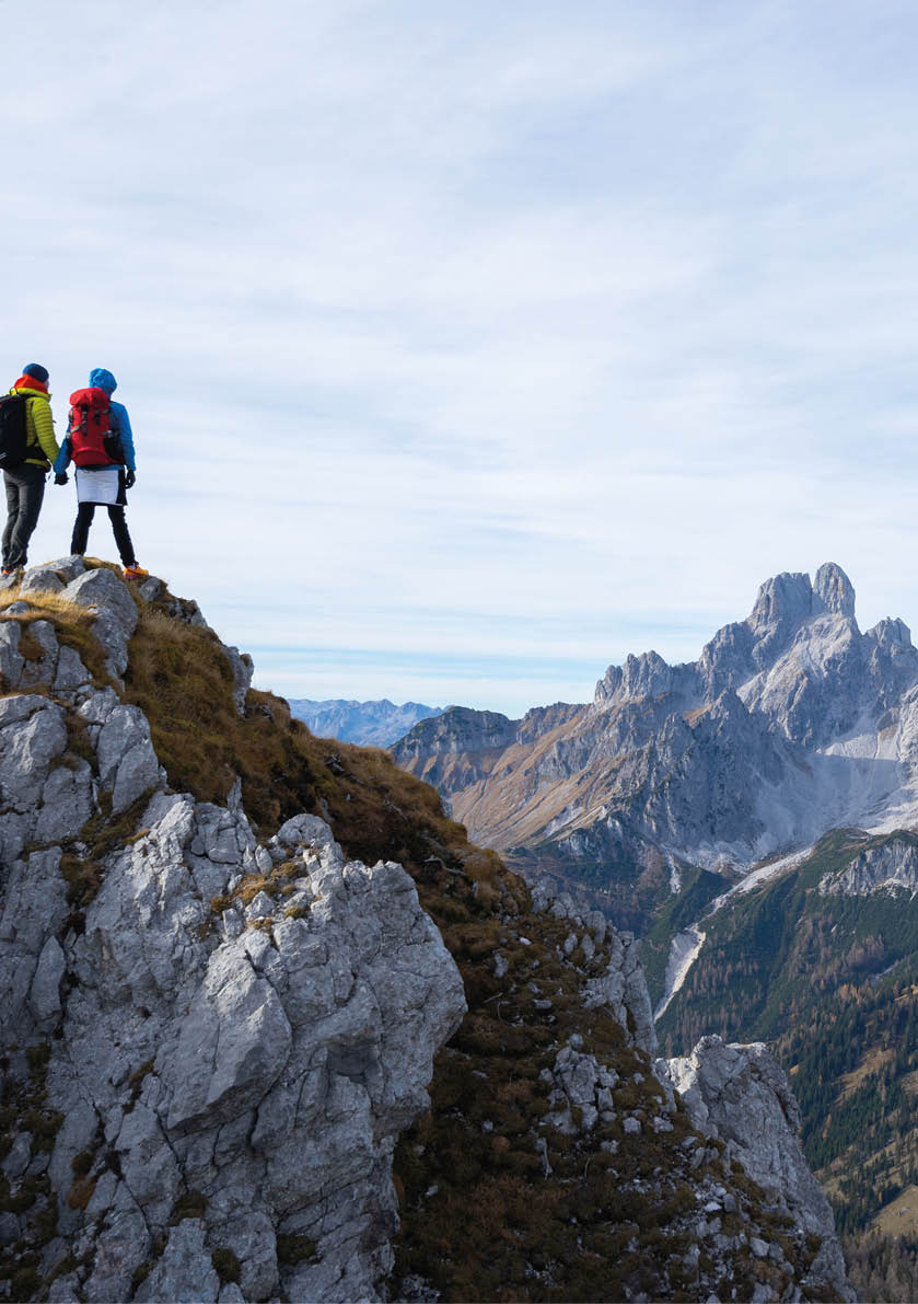 rear view mountaineers couple holding hands extreme hiker woman man with backpack and warm outdoor outfit standing togather high above in mountains on cold windy autumn day