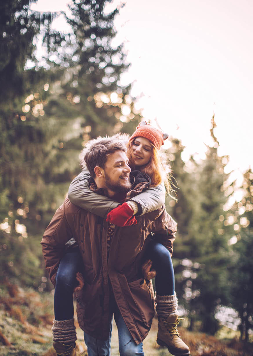 Couple on vacation hiking with a backpack in forest  Austrian Alps  Wearing warm clothes and enjoying in beautiful nature  Man piggybacking his girlfriend   Winter day 