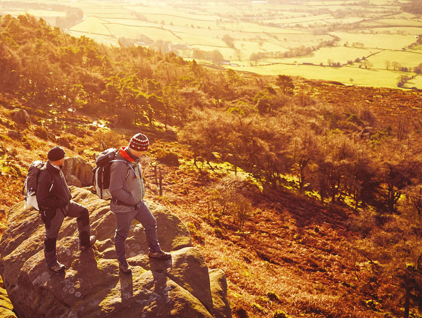 Top view of two men standing over a rock on mountain  Mature men hiking in mountains and looking at view 