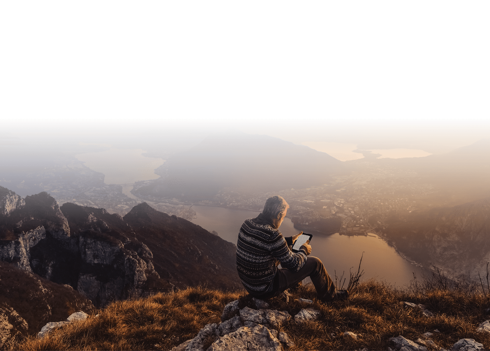 Man hiker solo on the mountain during golden hour reading e-book