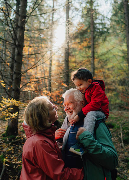 Photo of grandparents and their grandson having a walk through the forest