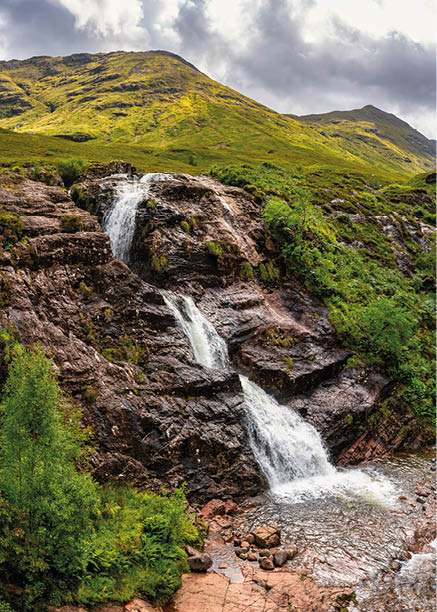 Stunning scenery with high mountains and three waterfalls converging in the Glencoe Valley, Scotland