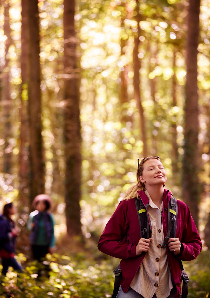 Woman Closing Eyes Enjoying Peace As Group Of Female Friends On Holiday Hike Through Woods Together