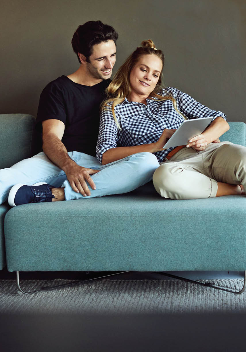 Shot of a cheerful young couple browsing on a digital tablet together while relaxing on a couch at home