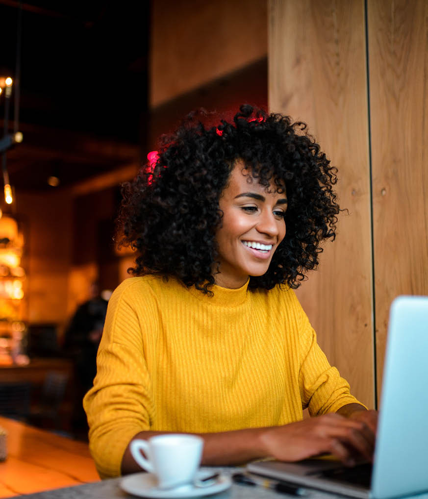 Beautiful smiling African American woman using laptop at the bar 