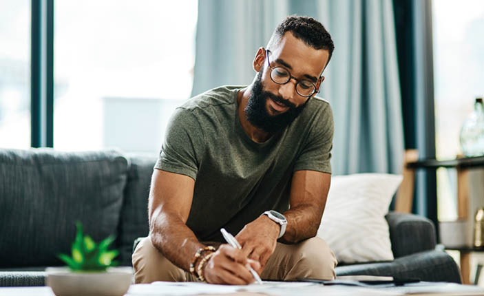 Shot of a young man going over his finances at home