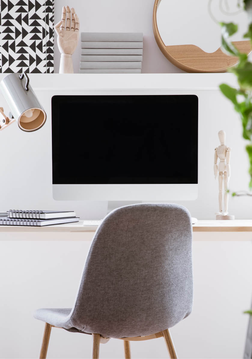 Grey chair at desk with lamp and desktop computer in simple white workspace interior  Real photo