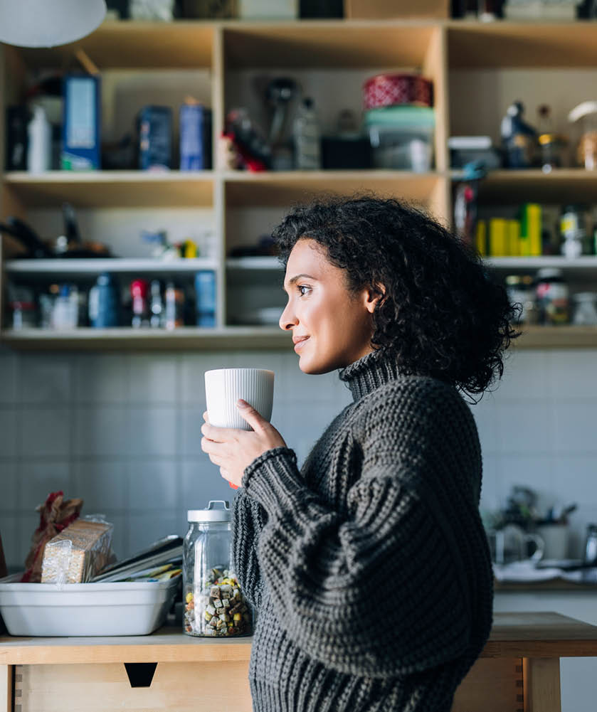 Simple pleasures at home: a beautiful young mixed race woman enjoying a cup of hot tea on a winter morning 