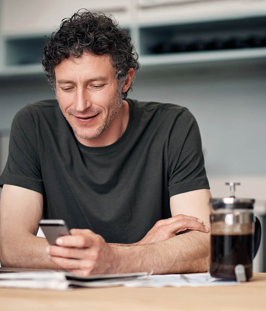 Shot of a mature man using a cellphone while going through paperwork at home