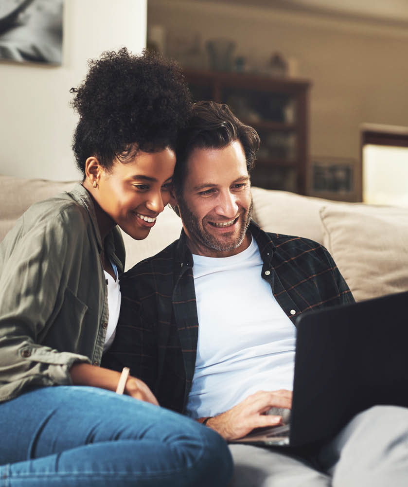 Shot of a happy young couple using a laptop while relaxing on a couch in their living room at home