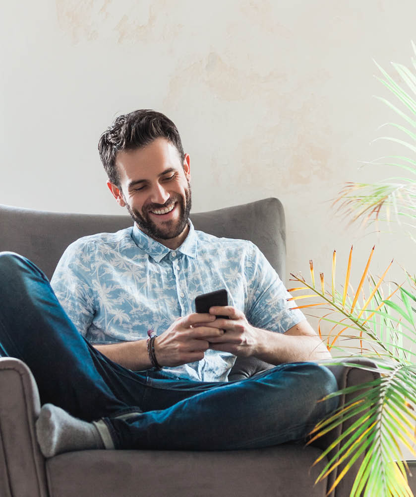 Young man using a smartphone sitting on the armchair